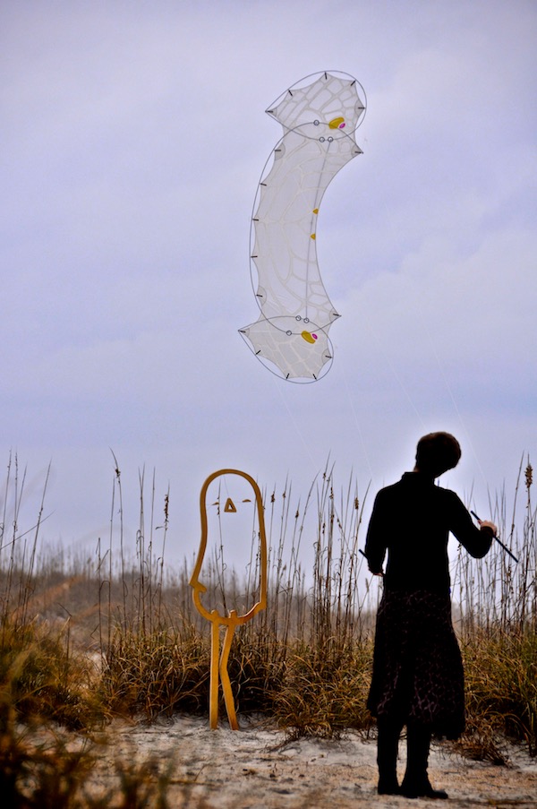 Ruth Whiting flies a kite she painted called a LaceWing Flame designed by Tim Elverston over a wooden cut out of Lonely Bird